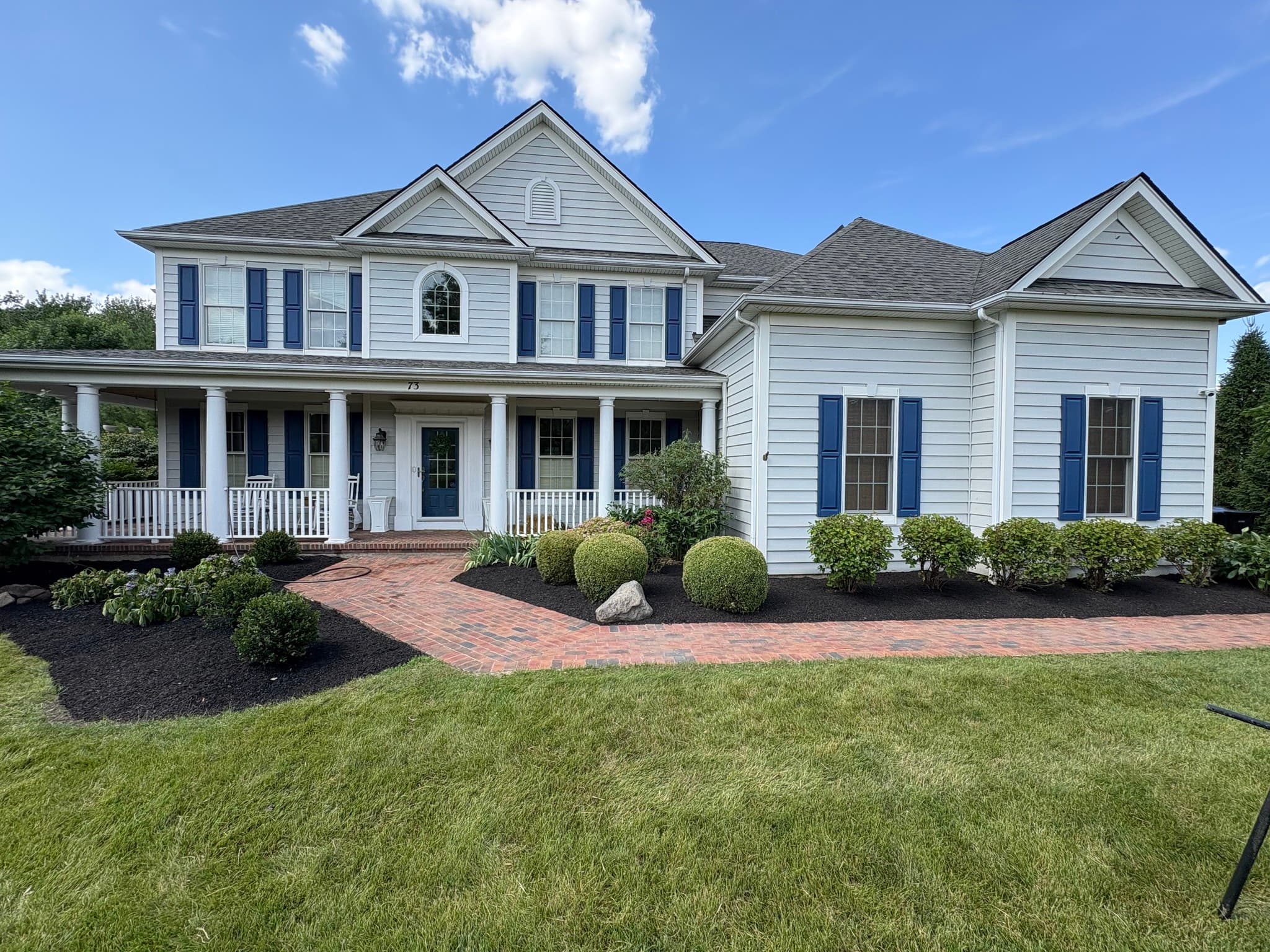 Beautiful residential landscaping - manicured lawn with mulch beds and brick walkway